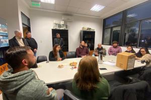 Reunión de un grupo de personas en una sala de oficina, sentadas alrededor de una mesa blanca