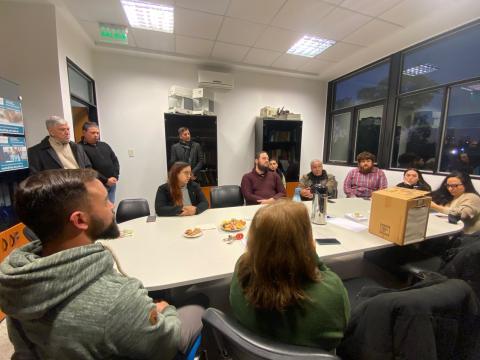 Reunión de un grupo de personas en una sala de oficina, sentadas alrededor de una mesa blanca