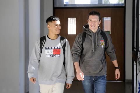 Dos estudiantes caminando por el pasillo de la facultad